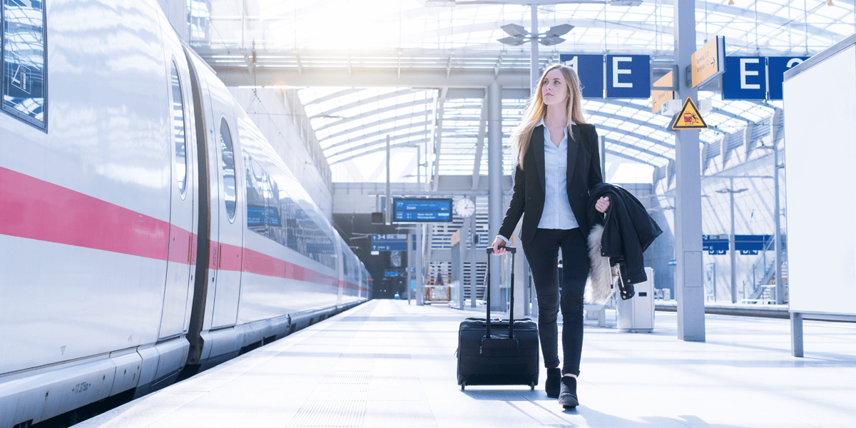 Geschäftsfrau mit Koffer an Bahnsteig geht an Intercity Express-Zug auf dem Bahnsteig entlang