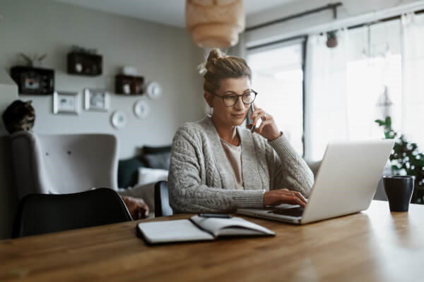 Geschäftsfrau im Homeoffice arbeitet an Laptop und telefoniert