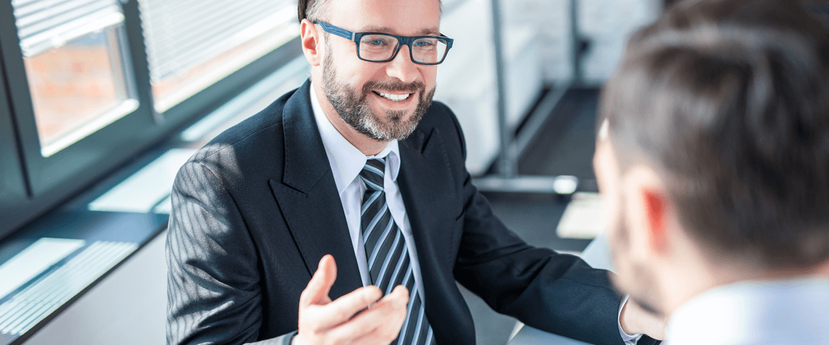 Geschäftsmänner in einem Meeting- oder Seminarraum sprechen über Unterlagen auf Klemmbrett 