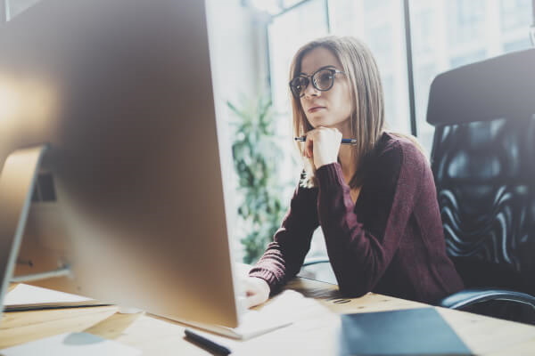 Junge Frau in einem hellen Büro blickt konzentriert auf den Monitor