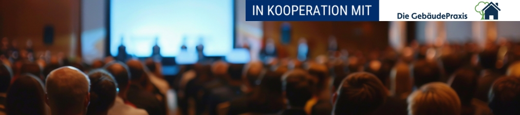 Publikum sitzt vor Bühne in einem großen Veranstaltungsraum mit Kooperationshinweis