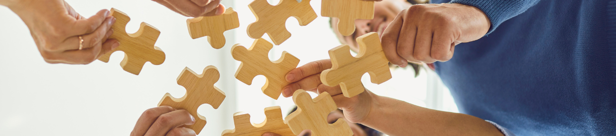 Hände halten Puzzleteile zusammen – Akademie Herkert